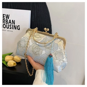 Detail of light blue floral embroidery and gold metal clasp on a vintage shell-shaped bag