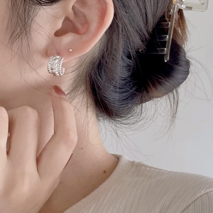 Minimalist 925 sterling silver twisted ear studs with irregular texture on a model