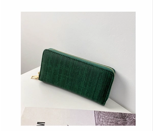 Detail view of the green long wallet with a wood grain texture and gold zipper hardware