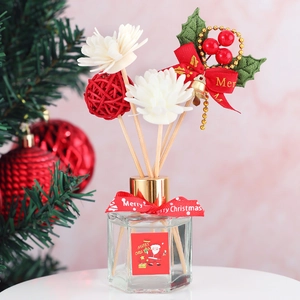 Christmas reed diffuser with red ribbon and berries in festive glass bottle decoration