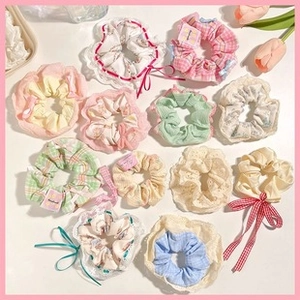 Detailed assortment of floral and lace fabric hair scrunchies on white tabletop
