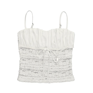 Close-up of white lace camisole featuring ruched bust detail and a silk ribbon bow