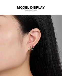Close-up of model wearing small 925 silver hoop earrings with white, green and purple zircons