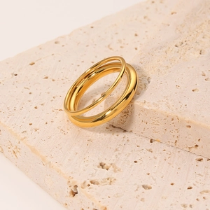 Polished double-layered golden hollow ring for women on a textured stone surface