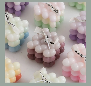 Top-down close-up of colorful bubble cube candles with decorative Best Wishes ribbons