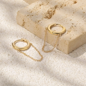 Detailed view of S925 silver gold chain hoop earrings on a beige stone background