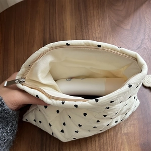 Detailed view of cream quilted corduroy makeup bag with heart pattern and zipper