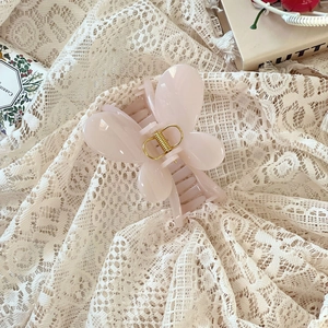 Détail de la pince à cheveux papillon rose avec ressort doré sur dentelle élégante