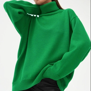 Détail d'un pull à col roulé vert clair avec texture côtelée et maille ample et douce