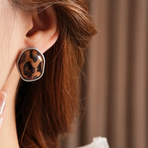 Gros plan de boucles d'oreilles léopard ovales avec bordure tressée en argent sur modèle