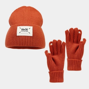 Detail of knitted orange hat and gloves set with letter patch and fingerless design