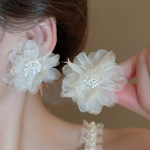Detail of cream tulle flower earrings with faux pearl center on model for elegant style