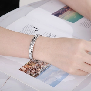 Detail of 9mm silver stainless steel wheat pattern open cuff bracelet on female wrist