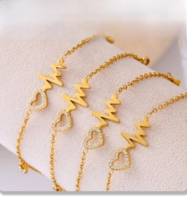 Close-up of four gold PVD electroplated anklets with zircon heart pendants on display