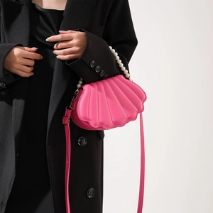Detail of pink shell-shaped crossbody bag with pearl handle and pleated texture