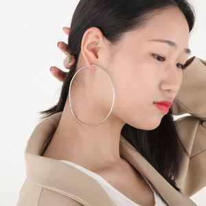 Close-up of extra-large polished silver hoop earrings on a model for a modern look