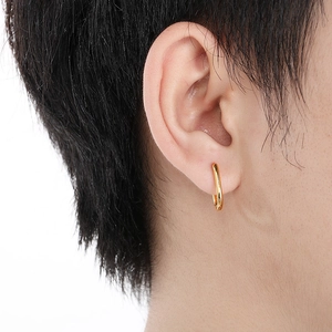 Gros plan d'un mannequin portant des boucles d'oreilles dorées en U en acier titane pur