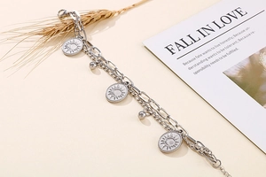 Detail of silver double-layer stainless steel bracelet with sun pendant and beads