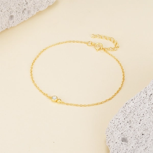 Macro detail of gold s925 silver bracelet featuring a zircon stone and metal beads
