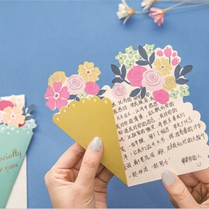 Detalle de tarjeta desplegable 3D de ramo con saludos escritos a mano y diseño floral de papel