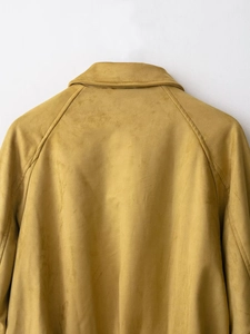 Detail shot of mustard yellow suede bomber jacket collar and textured shoulder area