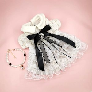 Elegant white tweed pet dress with lace trim and pearl necklace accessory on pink background