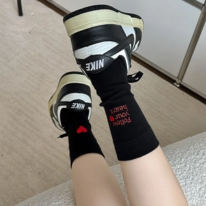 Detail shot of black knit socks featuring red heart and Follow your heart embroidery