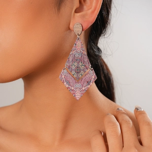 Ethnic bohemian wood earrings with rhombus design worn by a model in a close-up detail shot