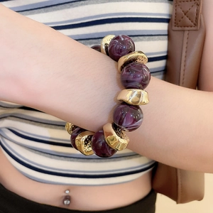 Macro detail of acrylic marble bead bracelet with irregular gold metal spacers on wrist