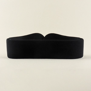 Detail of a wide black elastic waist belt with geometric metal buckle and textured fabric