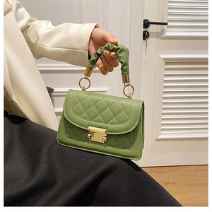 Detalle de bolso verde acolchado con asa fruncida y cierre metálico dorado cuadrado