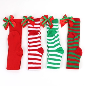 Detail of Christmas over-the-knee socks with festive bows and pom-poms on knit fabric