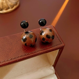 Close-up of leopard print ball studs on a brown leather jewelry case showcase