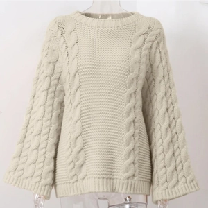 Detail of chunky cable knit texture on beige crewneck sweater with flare sleeves