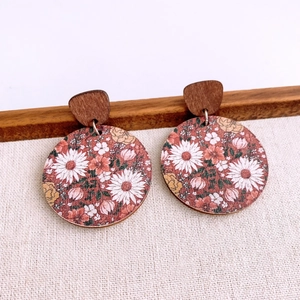 Detail of floral earrings with round daisy pattern and dark brown wood studs
