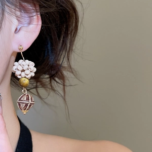 Detail view of retro ethnic earrings with tiger eye beads and wooden floral beads on model