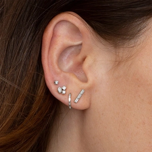 Macro shot of silver S925 sterling silver square diamond stud earrings on woman's ear