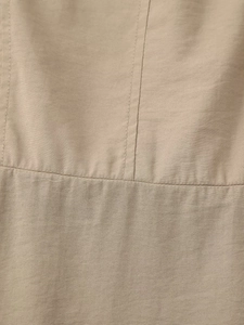 Detalle macro de la tela tejida caqui con costuras precisas y textura refinada