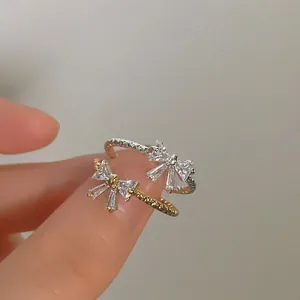 Adjustable 14K gold and silver bow rings with micro-set zircons on twisted bands