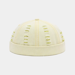 Close-up of distressed light beige docker hat featuring neon yellow frayed line details