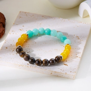 Macro shot of tiger eye and turquoise beads bracelet on beige stone textured background