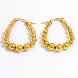 Macro shot of gold-plated stainless steel beaded hoop earrings on white background