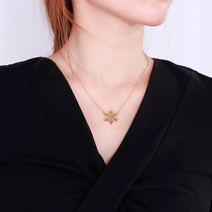 Elegant gold snowflake pendant necklace on model with minimalist V-neck outfit