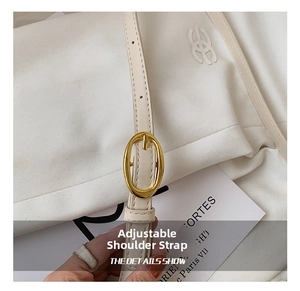 Detail of adjustable shoulder strap with gold metal buckle on cream baguette bag