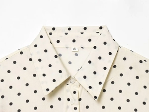 Detailed close-up of retro polka dot shirt collar and S size label on off-white fabric