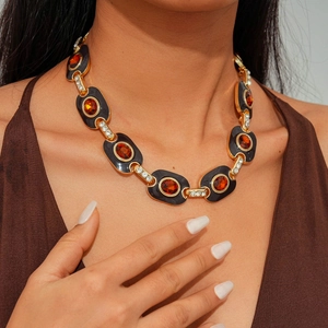 Detail of vintage gold necklace with orange oval gemstone and black enamel inlay