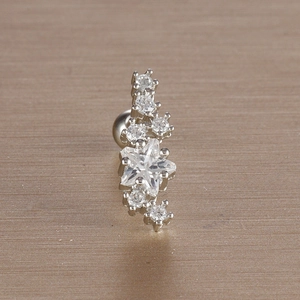 Macro shot of silver leaf-shaped ear stud with white zircon on metallic background