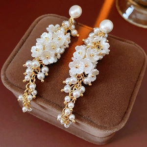 Macro shot of elegant floral tassel earrings with white resin petals and gold chains