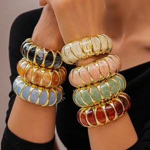 Close-up of colorful marbled resin acrylic bangles with golden alloy frames on a model wrist