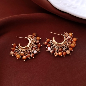 Detail of bohemian round beaded pendant earrings on vintage textured dark fabric